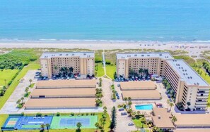 A hotel with multiple buildings, a swimming pool, and a beach in the background. - First Floor | Priv Beach | Pool & Pickleball (Cocoa Beach)
