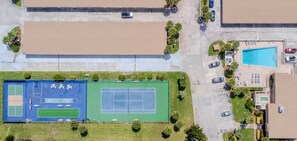 Eine Luftaufnahme einer Wohngegend mit Tennisplatz, Parkplätzen und Schwimmbad.