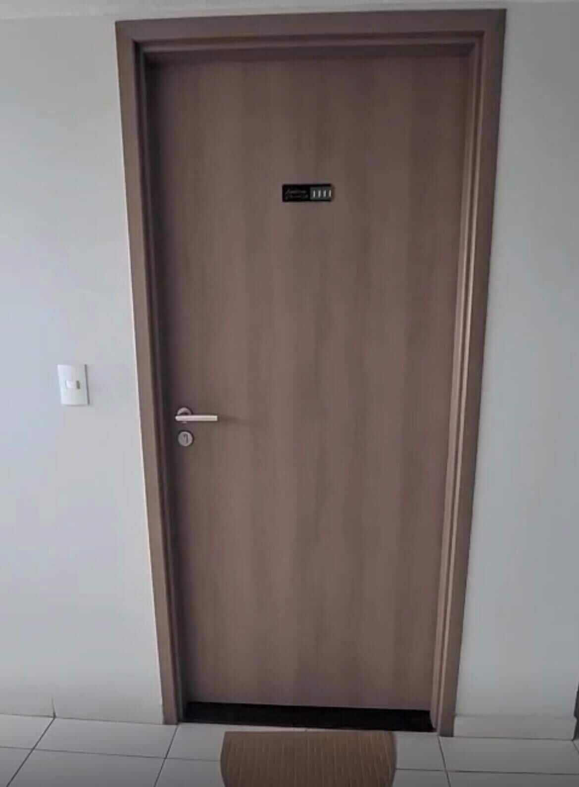 Una puerta de madera cerrada, con una manija y una pequeña señal encima.