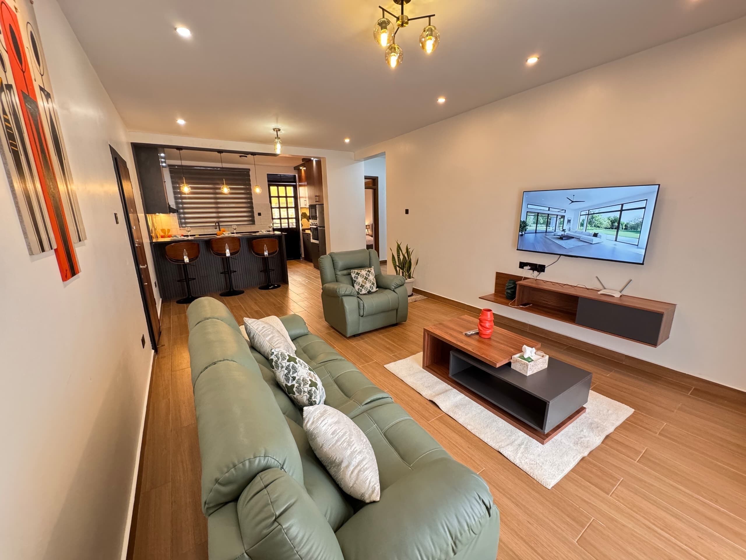 Una sala de estar moderna con un sofá verde, una mesa de centro y un televisor montado en la pared.