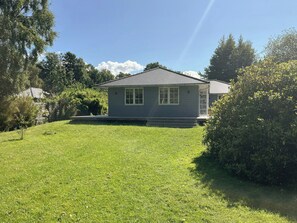 A single-story house with a front porch, surrounded by a well-maintained lawn and dense shrubbery. - Wooden house close to the sea in Hornbæk (Hornbæk)