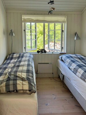 Ein Zimmer mit zwei Betten, einem Fenster mit Blick auf Grünflächen und einer Heizung.