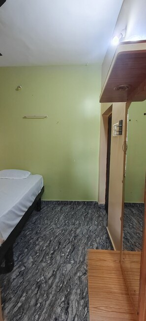 A room with a bed, a wooden wardrobe, and a door.