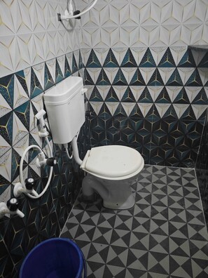 A bathroom with a toilet, a bidet, and a blue bucket.