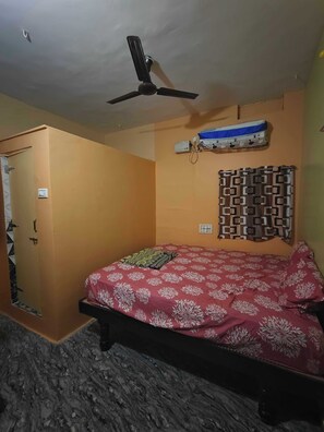 A bedroom with a bed, a ceiling fan, a wardrobe, and a wall-mounted air conditioner.