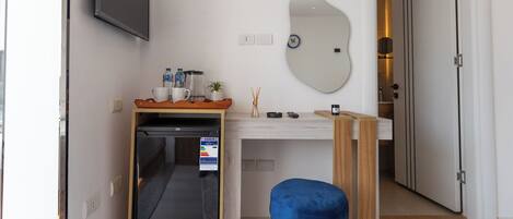 Una kitchenette compacta con lavavajillas, una mesita y un taburete azul.