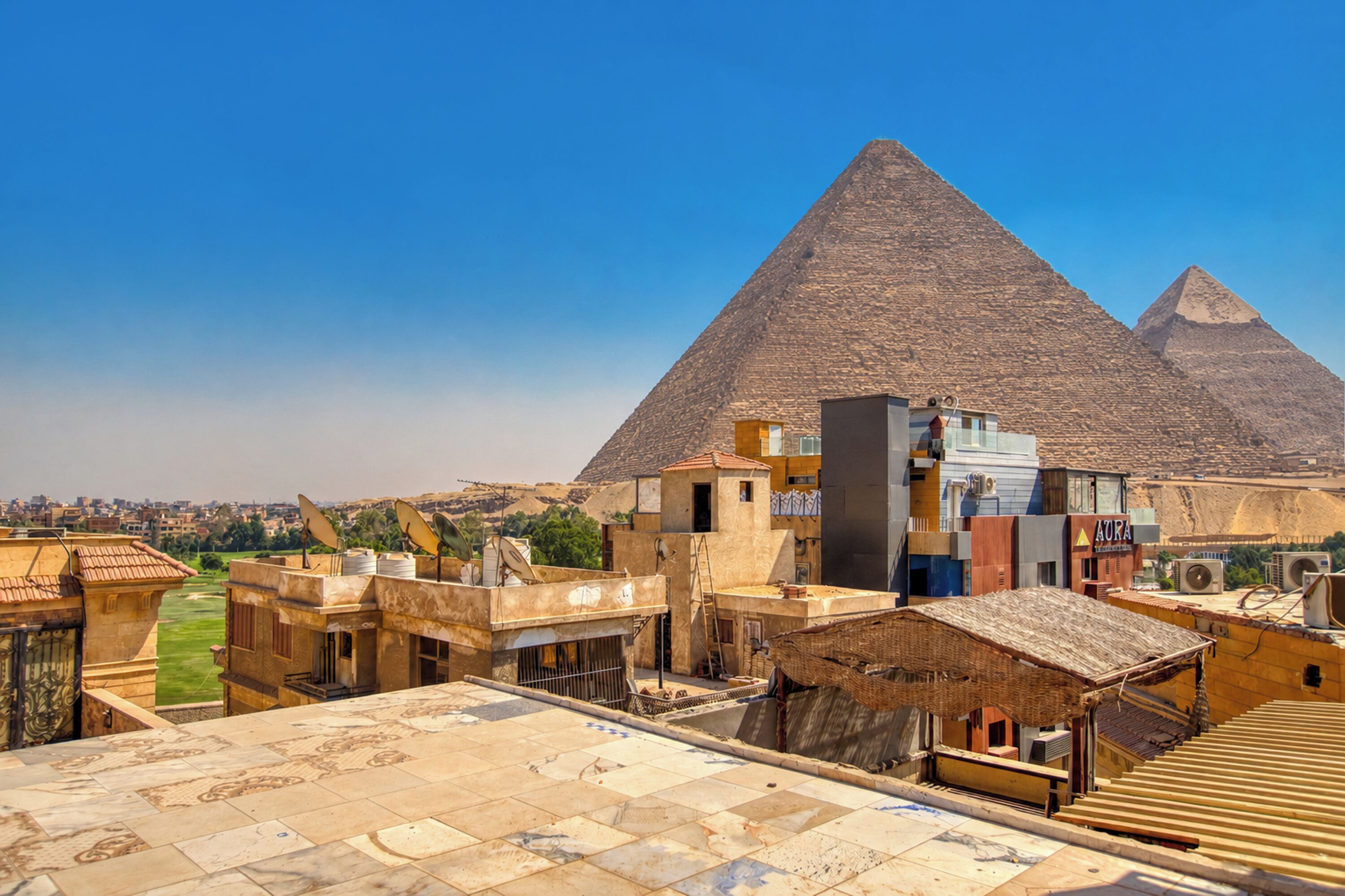 A view of the pyramids with modern buildings in the foreground.