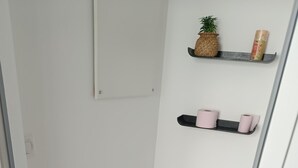Une petite salle de bain propre, avec des toilettes blanches, un plancher en bois et une étagère contenant des articles de toilette.
