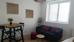 Un espace de vie moderne comprenant une table à manger, des chaises, un canapé, une petite table ronde et une plante en pot.