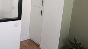 Une pièce avec une armoire blanche, une petite table ronde ornée d’une plante et un plancher en bois.