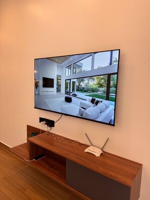 Un televisor de pantalla plana montado en la pared, con un mueble de madera debajo.