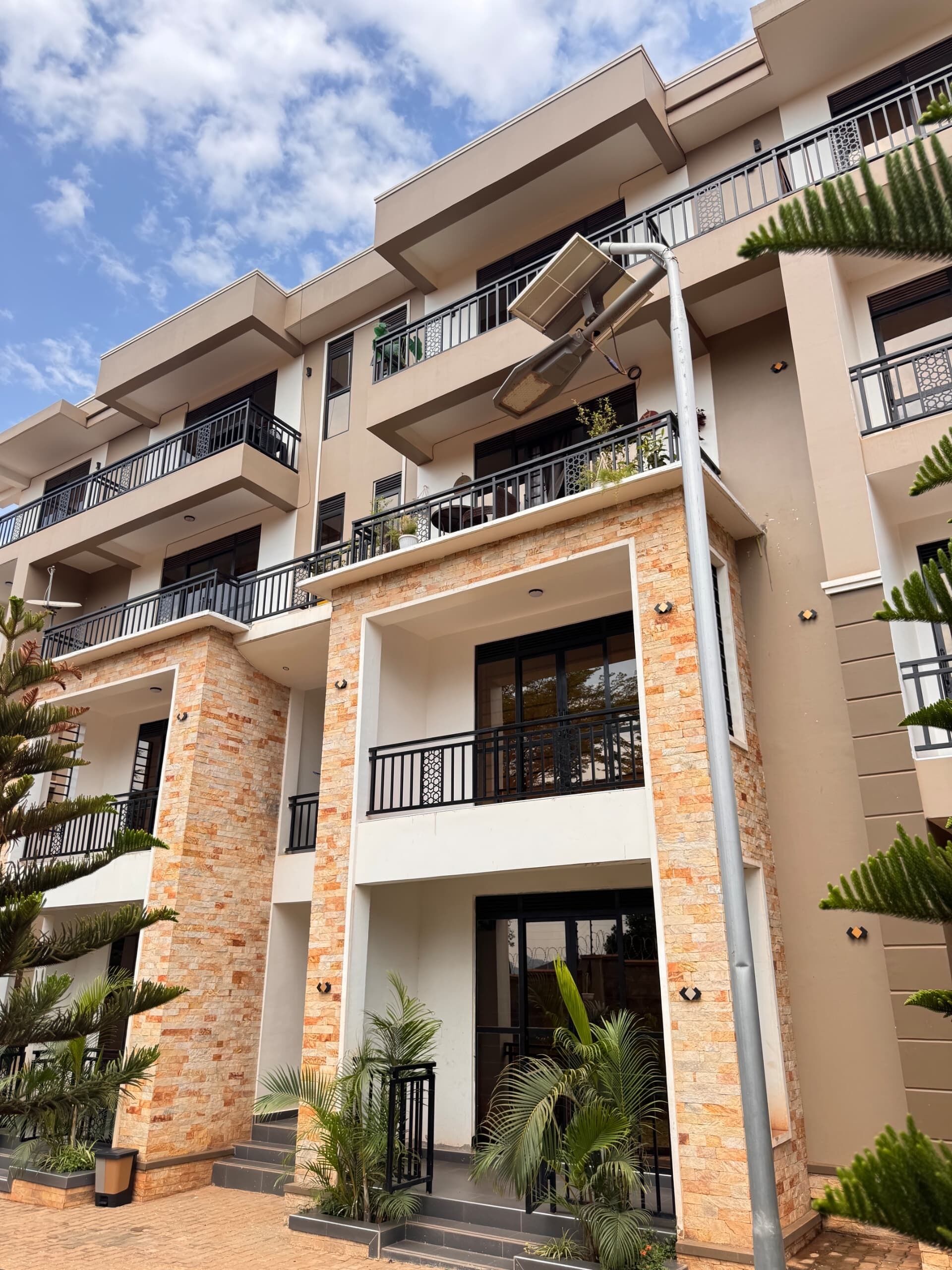A multi-story residential building with balconies, a brick facade, and a clear sky.