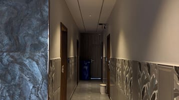 Ein Korridor mit einer Marmorwand auf einer Seite und einer Wand mit Muster auf der anderen, der zu einer Tür am Ende führt.