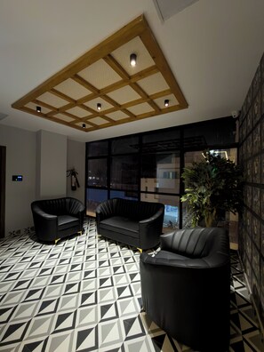 Un interior moderno con suelo de diseño geométrico, techo de madera con iluminación empotrada y asientos de cuero negro.
