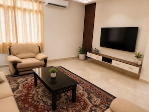 A living room with a sofa, a coffee table, a TV, and a patterned rug.