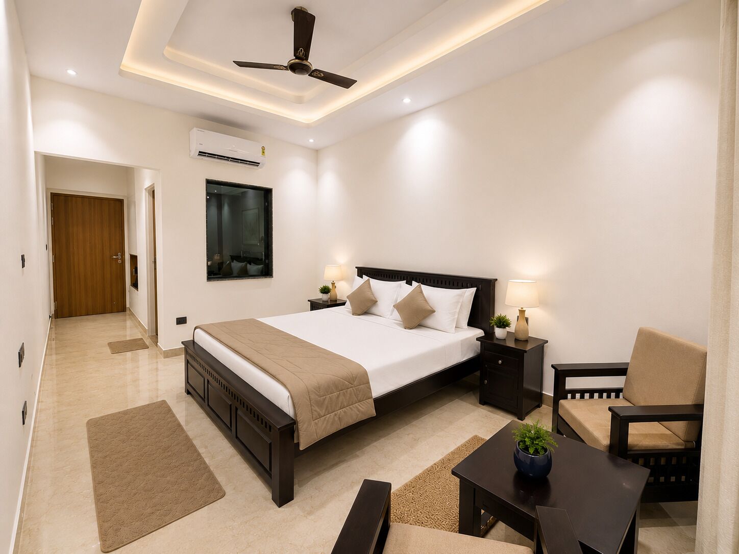 A hotel room with a bed, bedside tables, a chair, a desk, a ceiling fan, and an air conditioning unit.