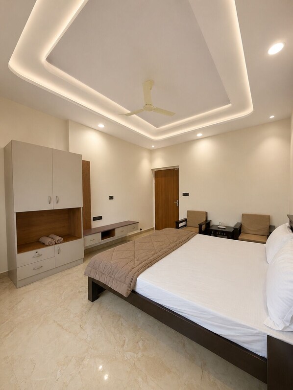 A modern bedroom with a large bed, built-in wardrobe, bedside tables, and a ceiling fan.