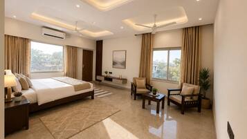 A modern hotel room with a large bed, a seating area with a coffee table, and a view of the outdoors.