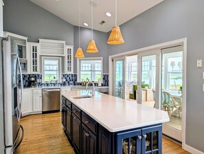 A modern kitchen with a large island, white cabinetry, and a view to the outside. - 18 South Shore Drive - South Shore Marina (Bethany Beach)