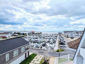 A marina with boats docked, a parking area, and residential buildings in the background. - 18 South Shore Drive - South Shore Marina (Bethany Beach)