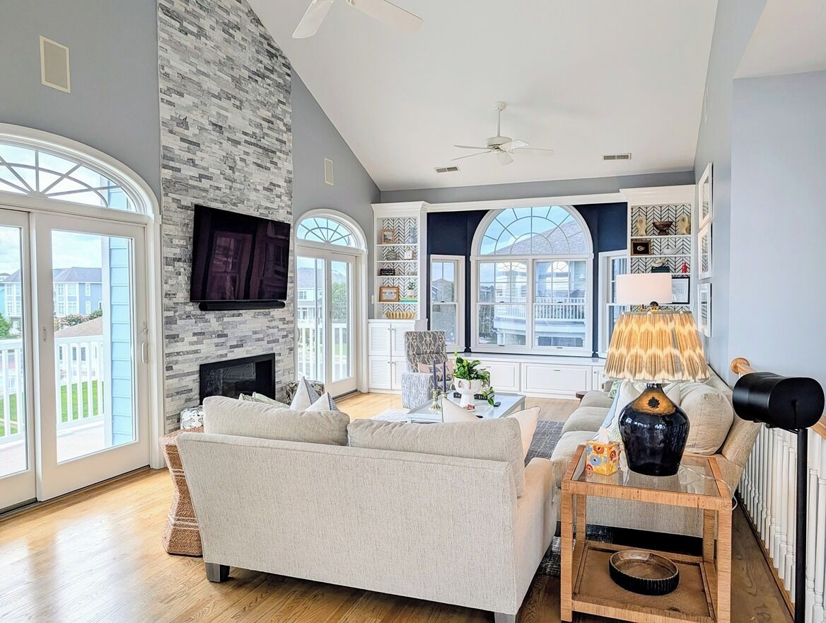 A spacious living room with a fireplace, a sofa, a coffee table, and a TV mounted on the wall.