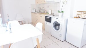 Eine moderne Küche mit Einbauwaschmaschine und -trockner, einem Esstisch mit Stühlen und einem Blumentopf.