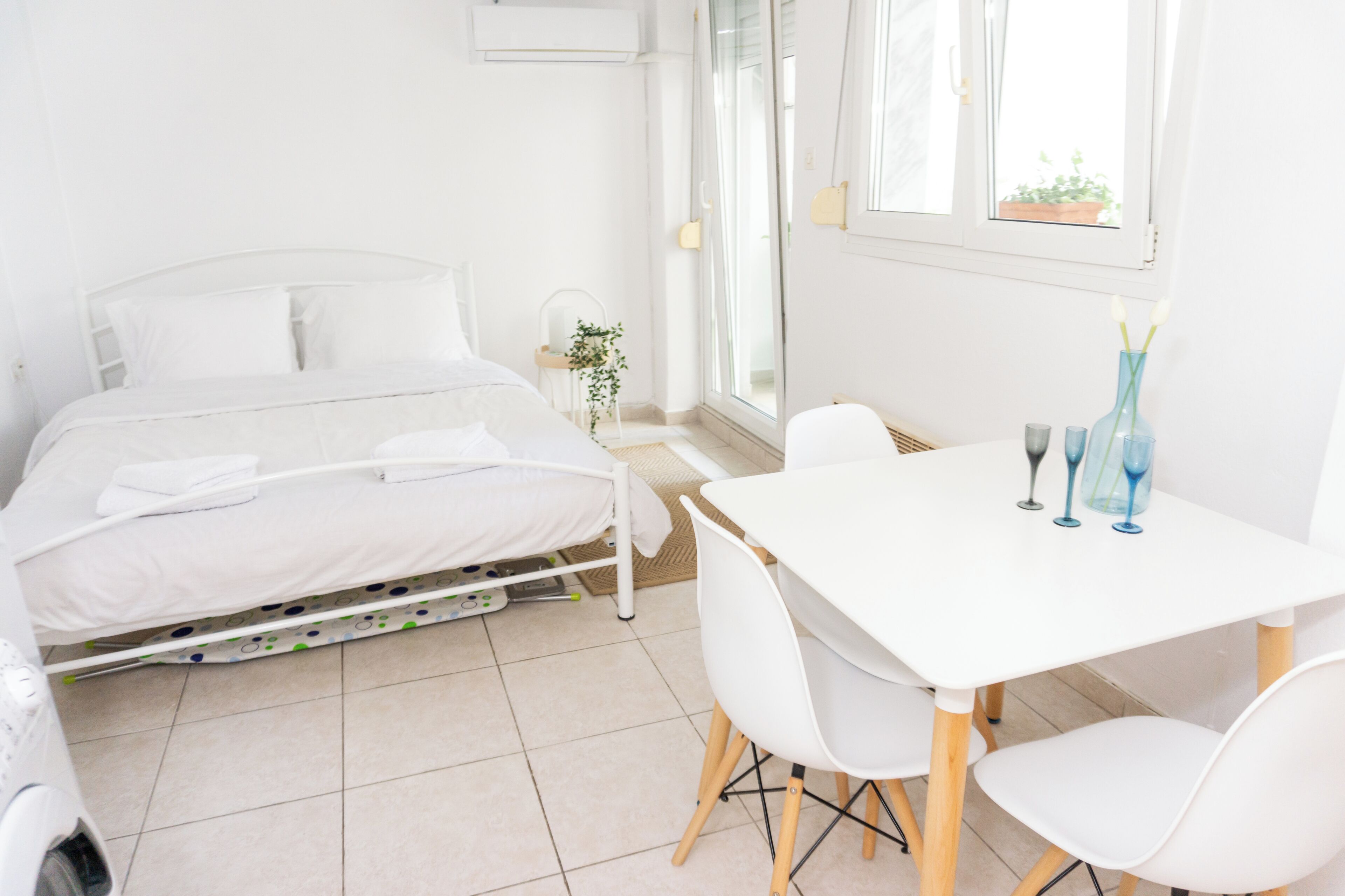 Habitación de hotel con cama, una mesa y sillas, una ventana con vistas y una planta.