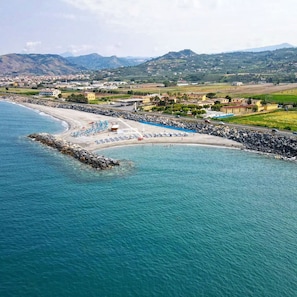 Eine Küstenlandschaft mit Strand, felsigem Ufer und einer entfernten Bergkette.