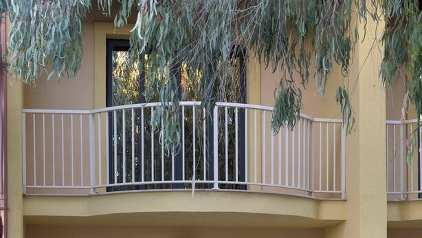 Un edificio a due piani con un balcone, un tavolo e sedie, e una porta.