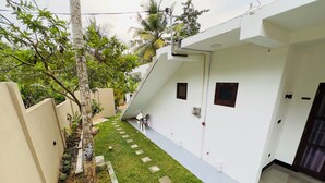 A modern building with a flat roof, a small courtyard with grass and potted plants, and a door with a window. - Private 2 Bedroom Villa with 2 King Beds Near Unawatuna Beach (Unawatuna)