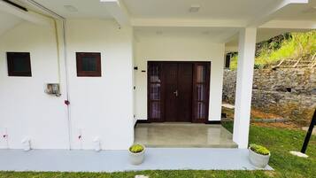 A modern house with a white exterior, a front door with glass panels, and two potted plants on the front porch.