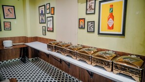 A restaurant with a long counter, multiple food service stations, and various framed pictures on the walls.