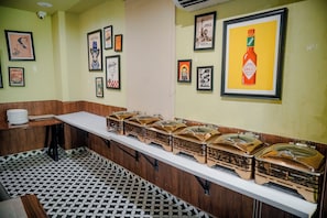 A restaurant with a long counter, multiple food service stations, and various framed pictures on the walls.