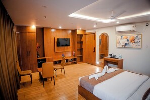 Una habitación de hotel con cama, escritorio, silla, televisor y armario.