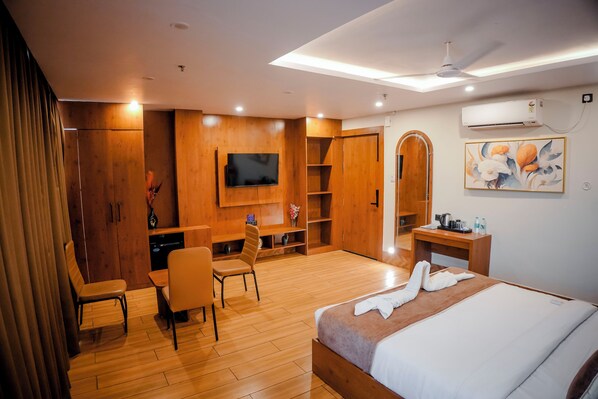 A hotel room with a bed, a desk, a chair, a television, and a wardrobe.