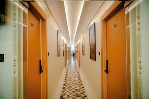 A hotel hallway with wooden doors, numbered room signs, and framed artwork on the walls.