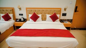 A hotel room with a large bed, two bedside tables, a red throw blanket, and a minibar.