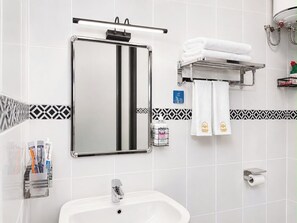 Ein Badezimmer mit Waschbecken, Spiegel, Handtuchhalter und Pflegeprodukten.
