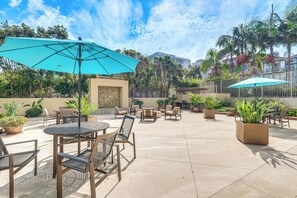 An outdoor patio area with round tables, chairs, and umbrellas. - Extended La Jolla Escape Steps From the Coast (La Jolla)