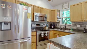 A modern kitchen with stainless steel appliances, wooden cabinets, and a granite countertop.