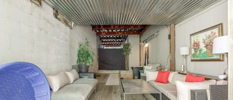 Ein überdachter Außenbereich mit einer Couch, einem Tisch und einem blauen Gegenstand.
