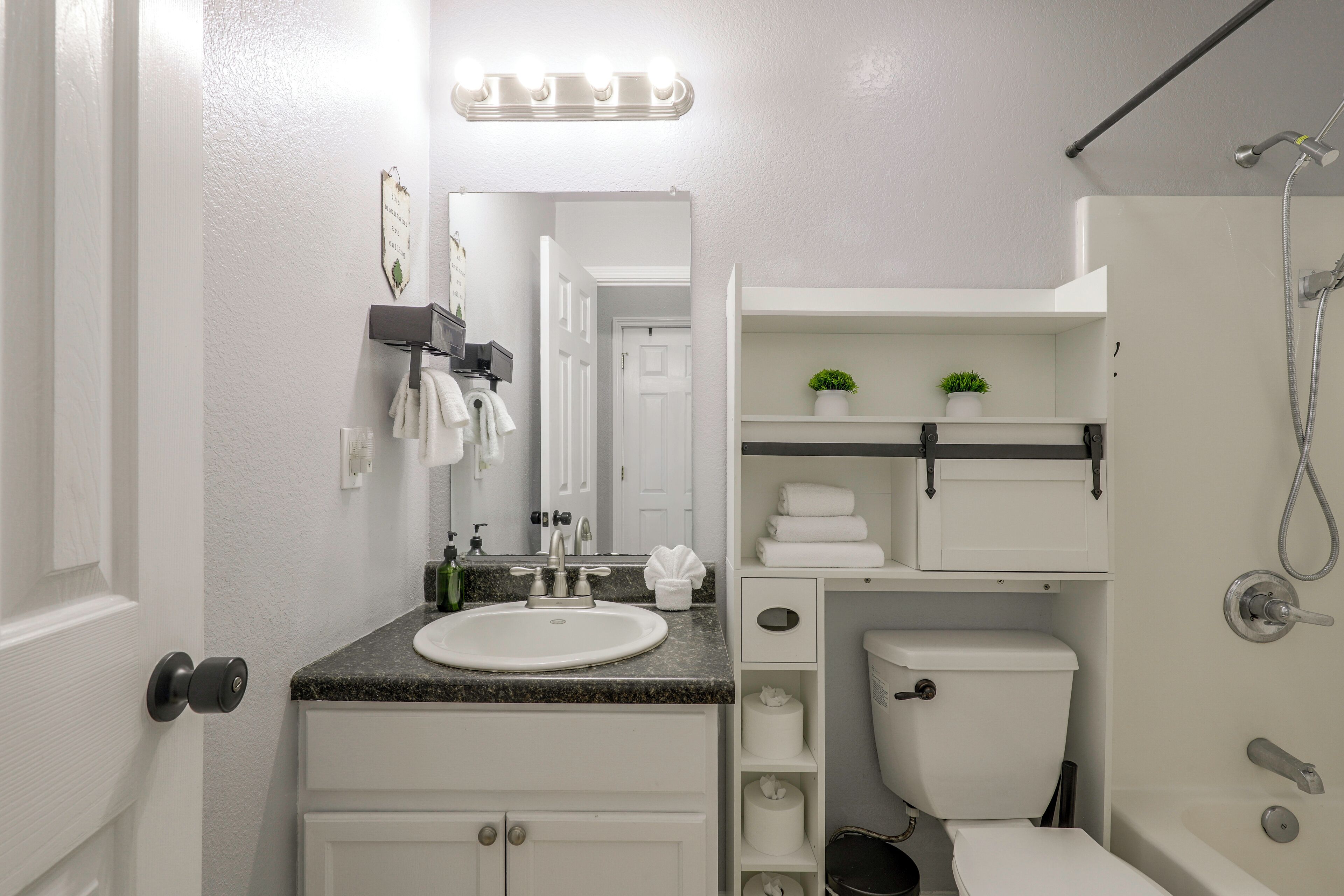 A bathroom with a white sink, mirror, and a shower area.