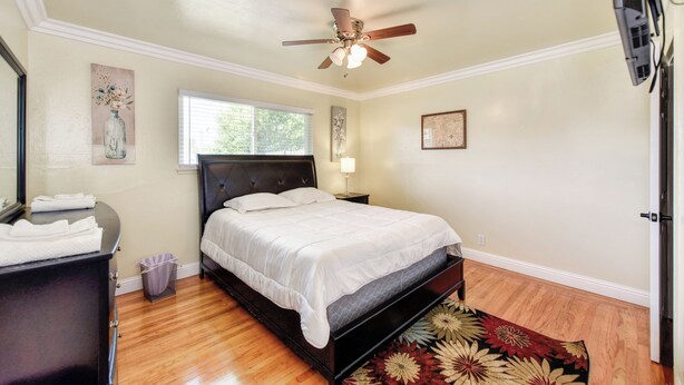 A bedroom with a bed, a ceiling fan, a window, and a wall-mounted lamp. - Pool Table! Spacious Home, 8 Mi to Dtwn Commons (Sacramento)