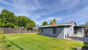 A residential property with a fenced backyard, a small house with a chimney, and a clear sky. - Pool Table! Spacious Home, 8 Mi to Dtwn Commons (Sacramento)