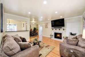 A living room with two sofas, a TV, a fireplace, and a dining area in the background. - Pool Table! Spacious Home, 8 Mi to Dtwn Commons (Sacramento)