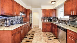 A kitchen with wooden cabinets, stainless steel appliances, and a patterned floor. - Pool Table! Spacious Home, 8 Mi to Dtwn Commons (Sacramento)