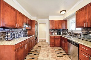 A kitchen with wooden cabinets, stainless steel appliances, and a patterned floor. - Pool Table! Spacious Home, 8 Mi to Dtwn Commons (Sacramento)