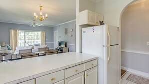 Een ruime keuken met een groot eiland, witte kasten en een geïntegreerde koelkast.