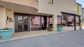 A hotel entrance with a curved facade, large glass doors, and potted plants. - Beachfront Condo! Heated Pool, Ocean-view Balcony (Daytona Beach Shores)