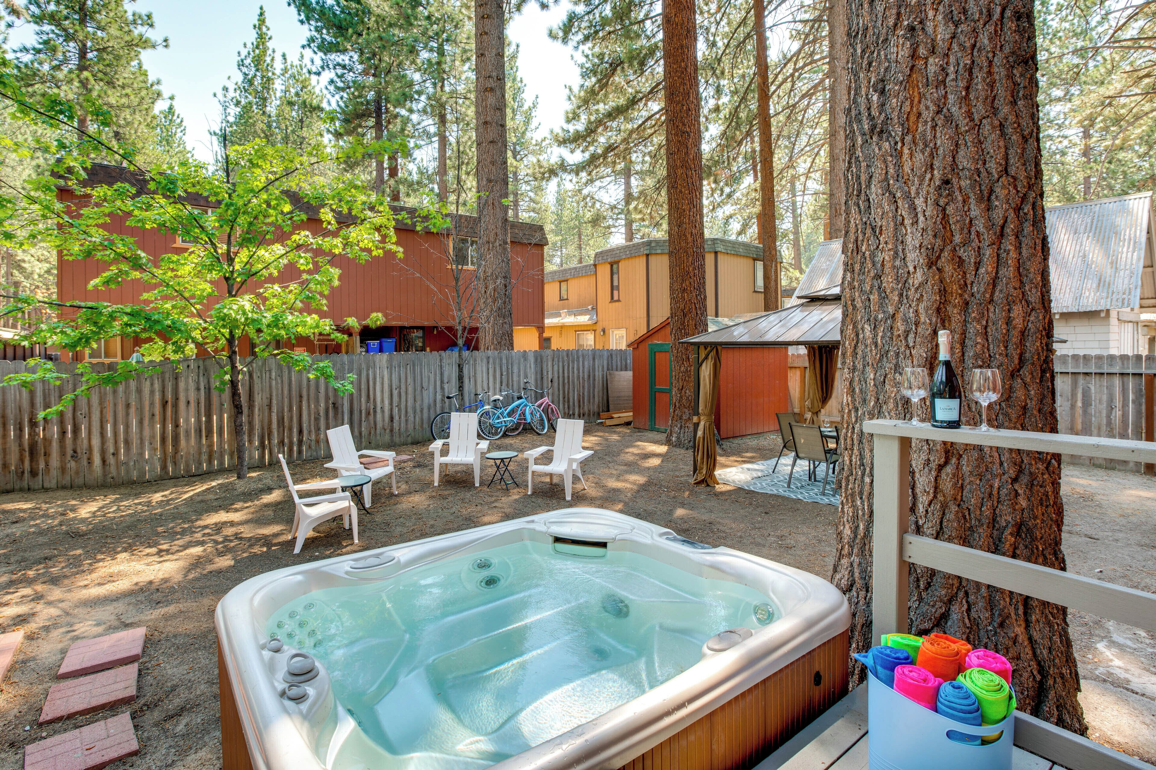 Un patio trasero con jacuzzi, mobiliario exterior y una terraza de madera.